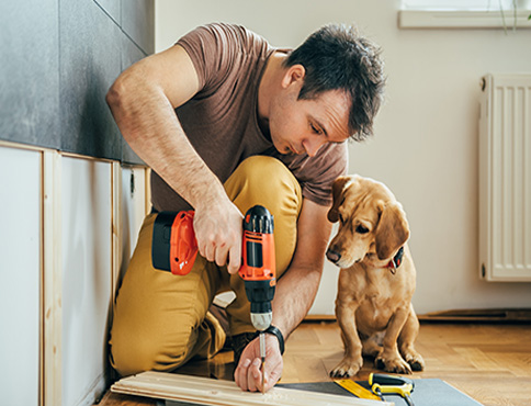 Man and his small dog doing some renovation work at home.